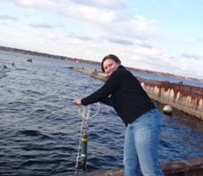 Angie Defore lowering a water quality sonde into Muskegon Lake
